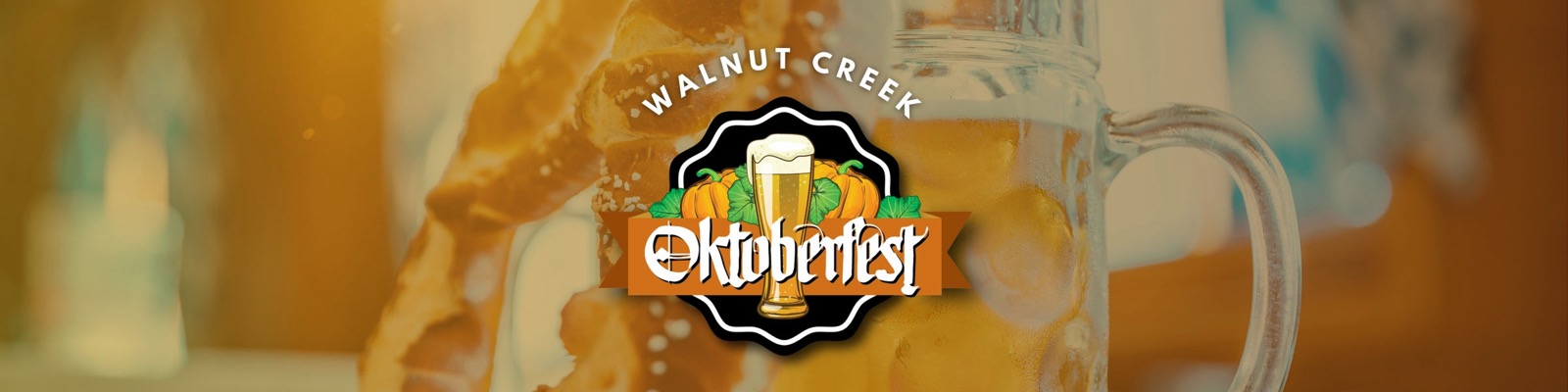 Walnut Creek Oktoberfest banner — the festival logo, a beer glass framed by pumpkins and leaves on a black badge with an orange Oktoberfest ribbon, over a soft-focus photo of a pretzel and a glass stein.